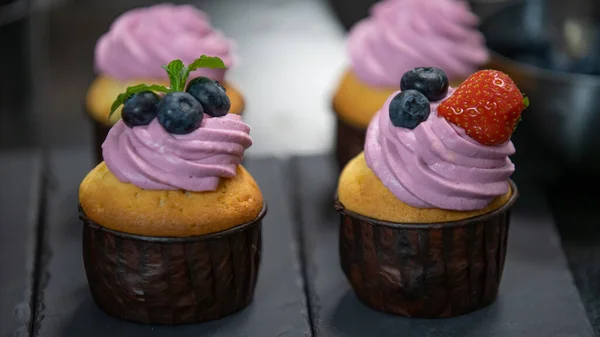 Cup cakes decorating with Strawberry. Butter cream on tasty muffins. Modern desserts and cakes. Cupcakes with cream filling. Professional pastry. Stock Photo