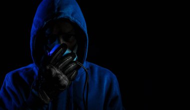 Güvenlik virüsü ağ kavramı karanlık arka planda eldiven ile mavi Hood kıyafeti ve maske ile kötü adam hacker