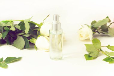 arka planda çiçek gül beyaz ve yeşil doğal yaprak ile açık parfüm kozmetik şişe cam paketi mockup