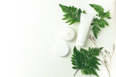 beyaz arka plan üzerinde yaprak eğrelti otu ile krem kozmetik tüp pakage mockup