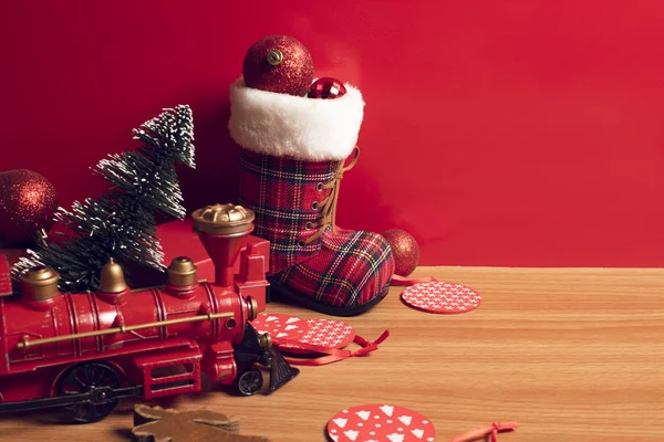 merry christmas with decor prop luxury toy and tree, train,snow boot,gloss ball on wood ground and red background