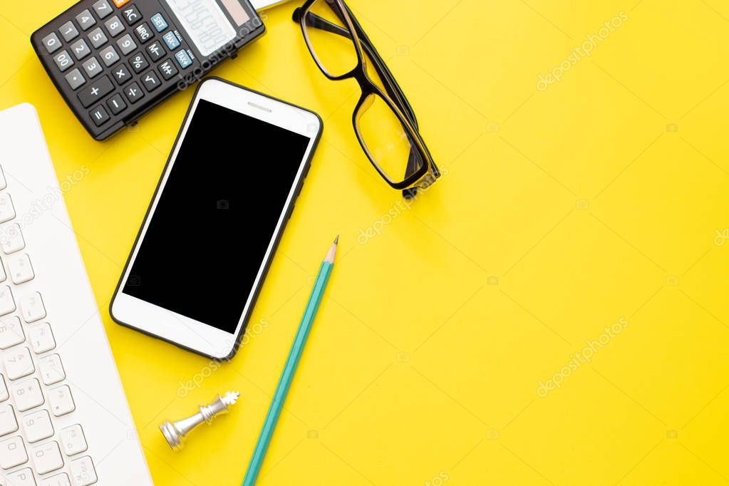 office business object calculator, pencil, mobile phone,chess, keyboard and eyeglasses on yellow background
