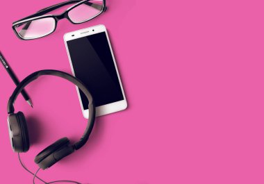 evde conncept iş pembe masa arka plan üzerinde gözlük ile pencila ve kulaklık ile akıllı telefon