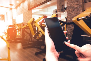 Spor kızı elinde cihaz tutan akıllı telefon uygulaması çalıştırıcısı sağlıklı konsept için vücut egzersizi yapan fitness jimnastik geçmişi olan