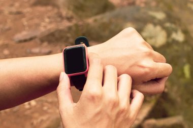 Akıllı adam aktivite çalışması için akıllı saat teknolojisini kullanıyor. Doğal orman arka planında macera yolculuğu hakkında bilgi veriyor.