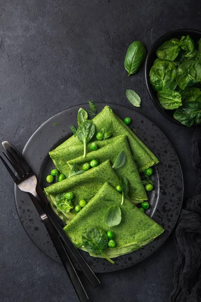 菠菜煎饼 黑盘子上有青豆 深色背景 顶部视图 — 图库照片