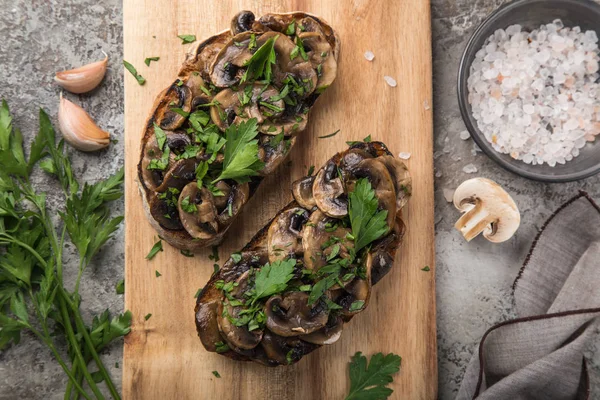 mushrooms garlic toasts on wooden cutting board, top view