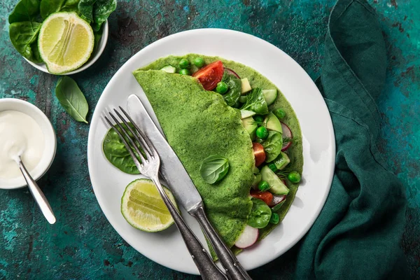 green spinach crepes with vegetables for breakfast, top view