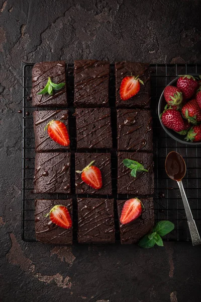 美味的巧克力布朗尼与新鲜的草莓在黑暗的背景 顶级视图 — 图库照片