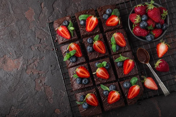 巧克力布朗尼与新鲜草莓和蓝莓在黑暗背景下 顶部视图 — 图库照片