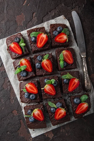 巧克力布朗尼与新鲜草莓和蓝莓在黑暗背景下 顶部视图 — 图库照片