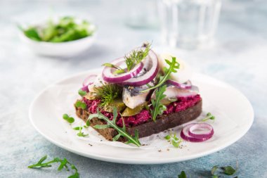open sanwich with dark rye bread, beet, marinated herring, pickled cucumber and red onion, smorrebrod, selective focus clipart