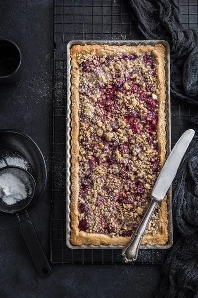 cherry and almond streusel tart, black background, top view