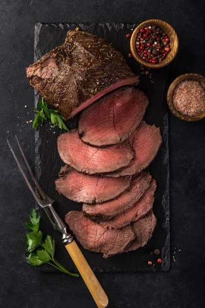 Carne Assada Fatiada Com Sal Pimenta Tábua Ardósia Fundo Preto — Fotografia de Stock