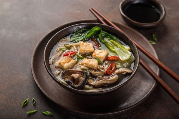 Asian vegan noodle soup with tofu cheese, shiitake mushroms and pak choi, dark background, selective focus — Stock Image Asian Vegan Noodle Soup Tofu Cheese Shiitake Mushroms Pak Choi Stock Picture