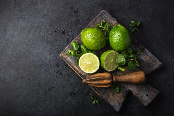 Frische Grüne Limette Und Minze Auf Holzschneidebrett Schwarzer Hintergrund Draufsicht — Stockfoto