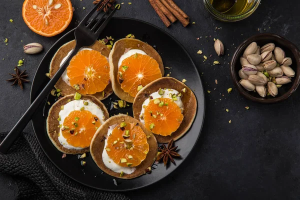 Heerlijke Pannenkoeken Met Clementines Crème Pistachenoten Zwarte Plaat Bovenaanzicht — Stockfoto