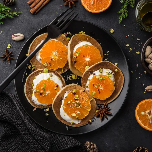 Deliciosos Panqueques Con Clementinas Crema Pistachos Plato Negro Vista Superior —  Fotos de Stock