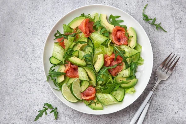 Авокадо, копченый лосось и огуречный салат на белой тарелке — стоковое фото