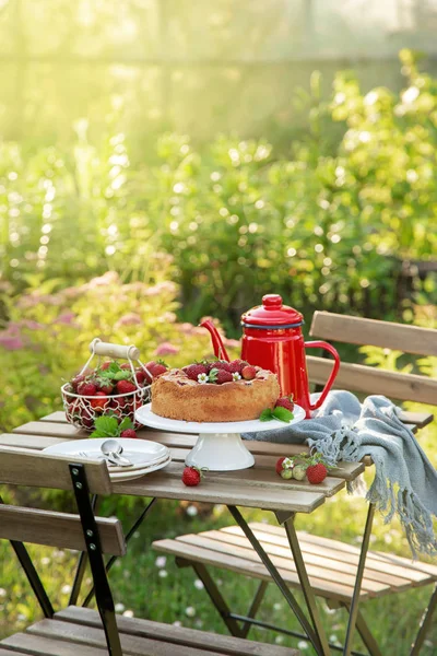 Ajuste de mesa con pastel de fresa de verano en un jardín — Foto de Stock