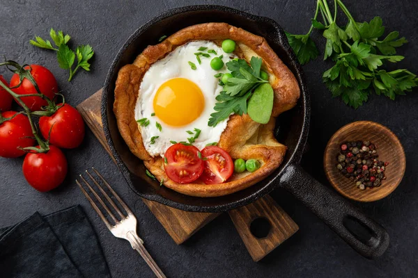 Savory Dutch baby pancake with fried egg, tomato and green peas — Stock Photo, Image