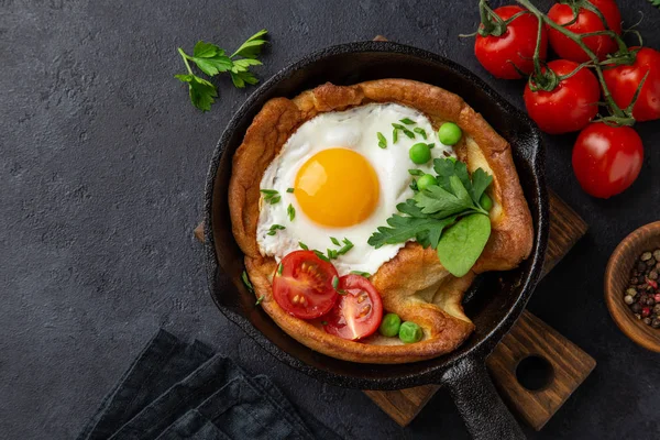 Savory Dutch baby pancake with fried egg, tomato and green peas — Stock Photo, Image