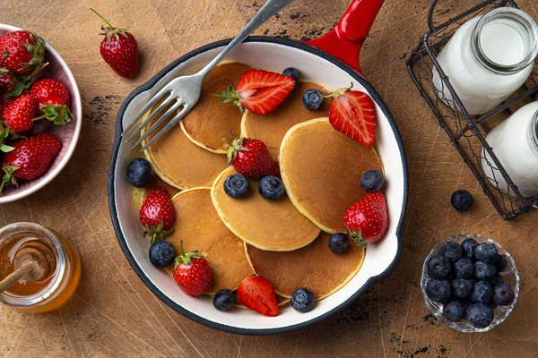 Pfannkuchen mit frischen Beeren und Honig in roter Pfanne zum Frühstück — Stockfoto