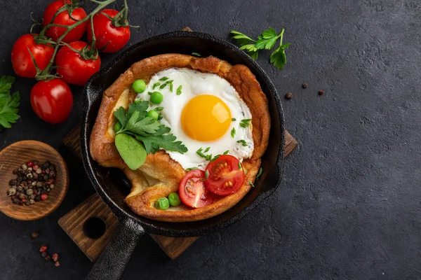 Savory Dutch baby pancake with fried egg, tomato and green peas — Stock Photo, Image