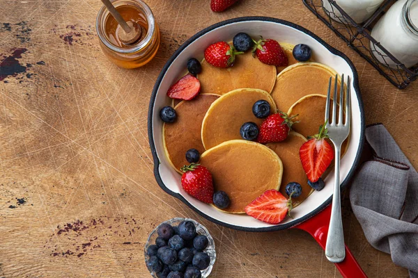 Pancakes with fresh berry in red pan for breakfast — Stock Photo, Image