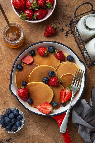 Pfannkuchen mit frischen Beeren und Honig in roter Pfanne zum Frühstück — Stockfoto