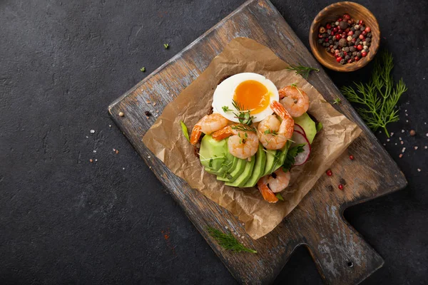 Open sanwich with dark rye bread, avocado, shrimps and soft boil — Stock Photo, Image
