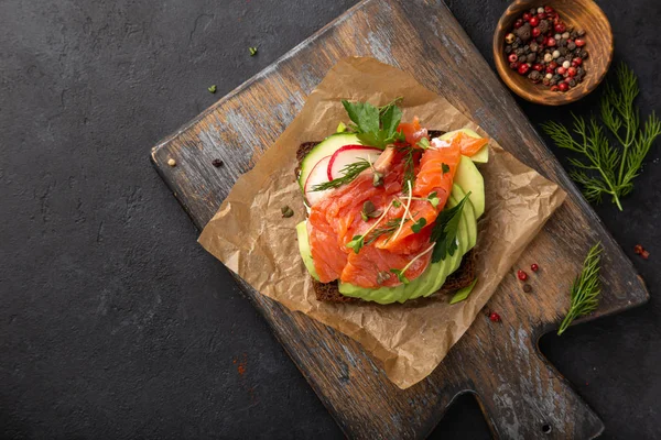 Sanwich abierto con pan de centeno oscuro, aguacate, salmón ahumado y rad — Foto de Stock