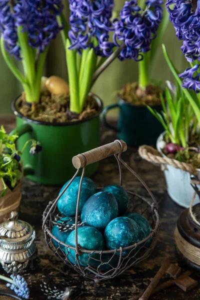 Colored blue Easter eggs in vintage basket with spring flowers — Stock Photo, Image