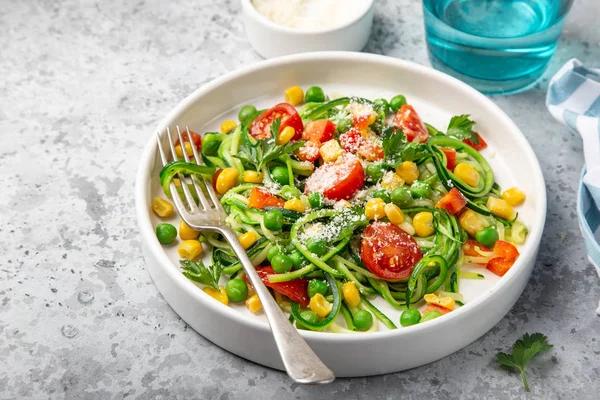 Tagliatelle di zucchine con pomodoro, mais e piselli verdi su piatto bianco — Foto Stock