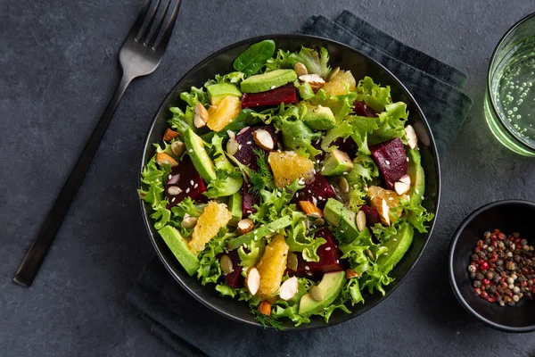 Salada saudável vegan abacate, laranja e beterraba em tigela preta, escuro — Fotografia de Stock