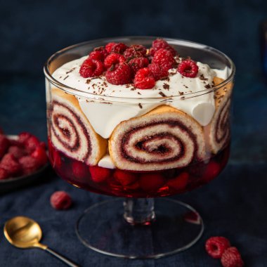 Raspberry trifle with berry jelly, swiss roll cake and whipped c clipart