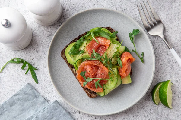 Toast with dark rye bread, avocado, smoked salmon and cucumber — ストック写真