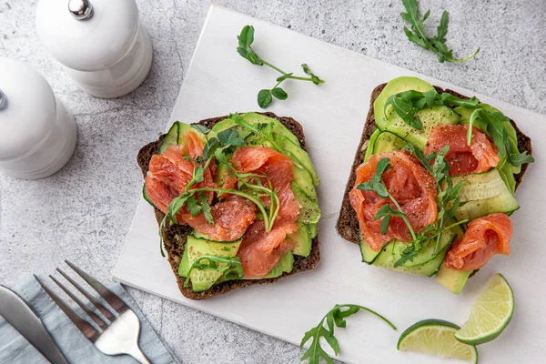 Toast met donker roggebrood, avocado, gerookte zalm en komkommer — Stockfoto