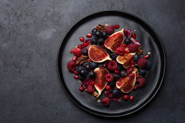 Feigen, Trauben, Himbeeren und Granatapfel Salat auf schwarzem Teller — Stockfoto