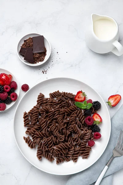 Pasta de fusilli de chocolate con bayas frescas en plato blanco —  Fotos de Stock