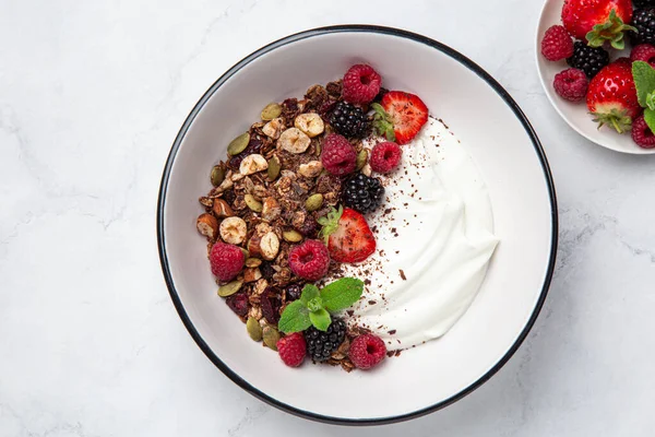 Schokoladen-Müsli mit Joghurt und frischen Beeren in weißer Schüssel — Stockfoto