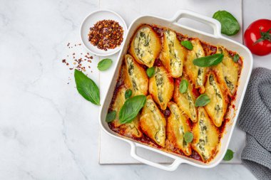 Ricotta and spinach stuffed shell  pasta with tomato sauce in white baking dish, white background, top view clipart