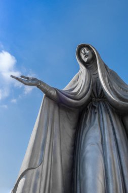 Meryem Ana heykeli bronz, mavi gökyüzü arka plan beyaz bulutlar, uzanmış kollarıyla ile.