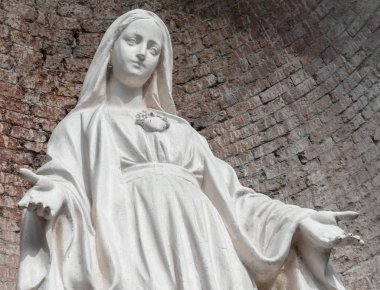 Taş Meryem Ana heykeli. Arka plan, kırmızı tuğla duvara. Noel ve Paskalya kavramları için ideal ve diğer.
