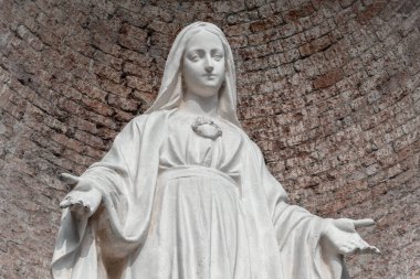Taş Meryem Ana heykeli. Arka plan, kırmızı tuğla duvara. Noel ve Paskalya kavramları için ideal ve diğer.