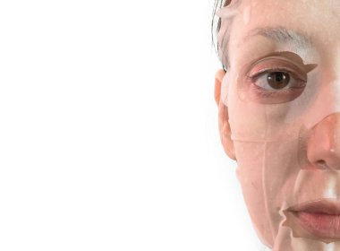 Genç bir kadın kozmetik doku maskesi takıyor. 