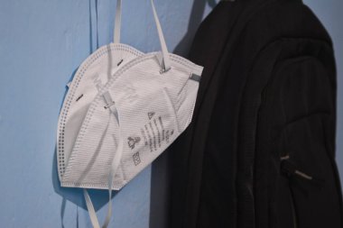  Sırt çantası ve ağızlar karantina sırasında okula dönmek için elbise askısına asılmış..