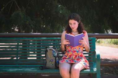 Bankta oturan ve notlar okuyan bir kız..