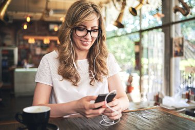 kafede oturan ve Smartphone cep telefonu ile tarassut genç sarışın kadın