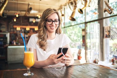 kafede oturan ve Smartphone cep telefonu ile tarassut genç sarışın kadın